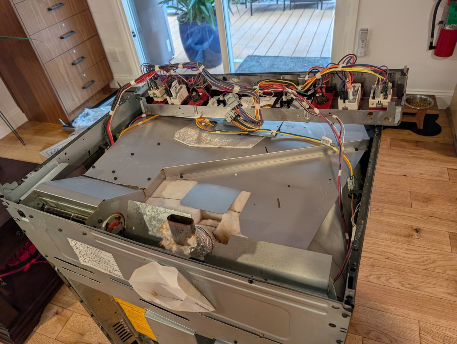 Why You Shouldn’t Cook on a Cracked Glass Stove (And Exactly How We Fix It) 12 The back panel of an electric stove removed to show the intricate control board and wiring harness.